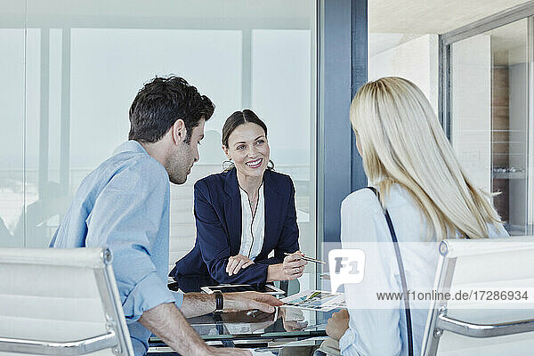 Lächelnde Verkäuferin im Gespräch mit einem Paar am Tisch sitzend