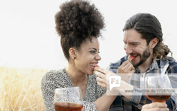 Couple with drink feeding strawberries to each other