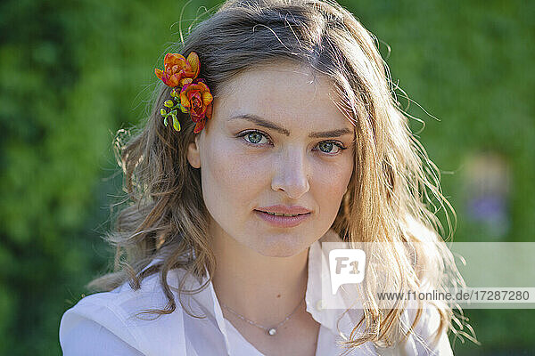 Schöne junge Frau mit braunem Haar trägt Freesie Blume während sonnigen Tag