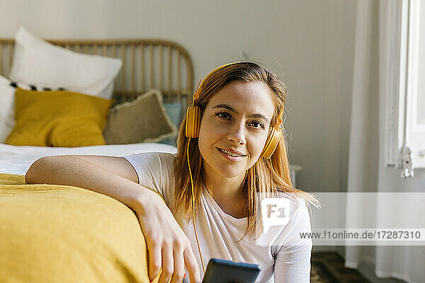 Young woman listening music through headphones at home