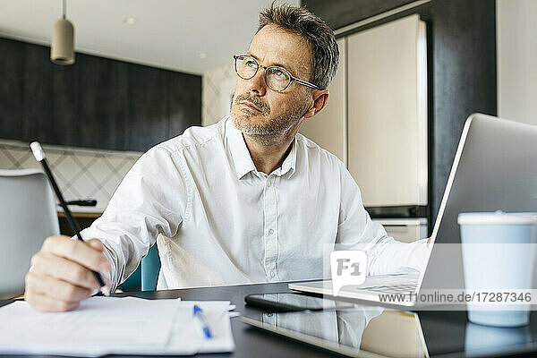 Businessman contemplating while working at table in home office