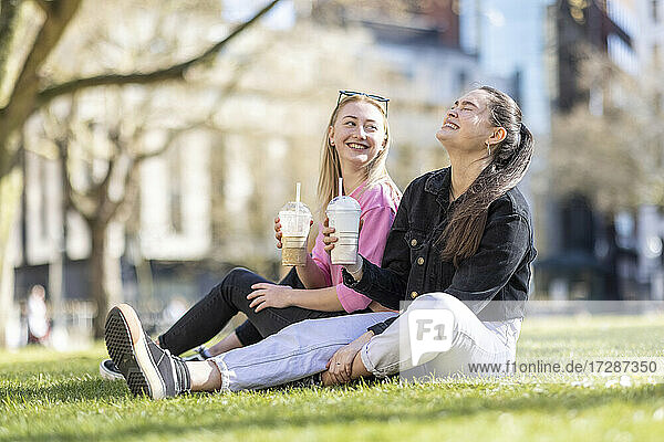 Fröhliche Freundinnen trinken einen Milchshake im öffentlichen Park