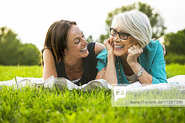 Glückliche Enkelin und Großmutter liegen im Park auf der Vorderseite
