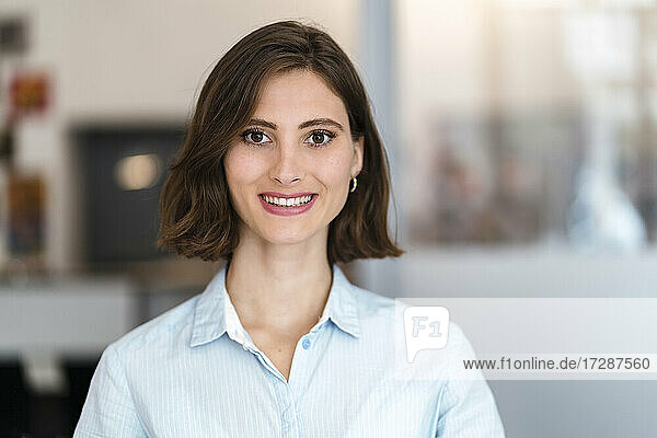 Schöne lächelnde junge weibliche Fachkraft mit braunen Haaren im Büro