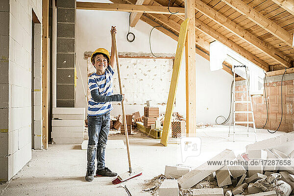 Junge mit Schutzhelm beim Hausputz während der Renovierung