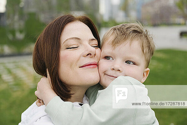 Niedlicher Sohn umarmt Mutter im öffentlichen Park