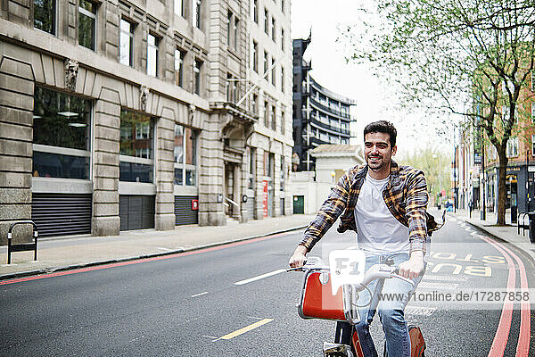 Smiling young man cycling on road in city