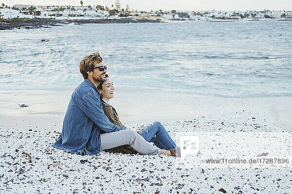 Mittleres erwachsenes Paar entspannt sich gemeinsam am Strand