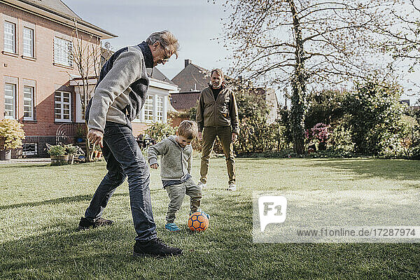 Family playing soccer in backyard