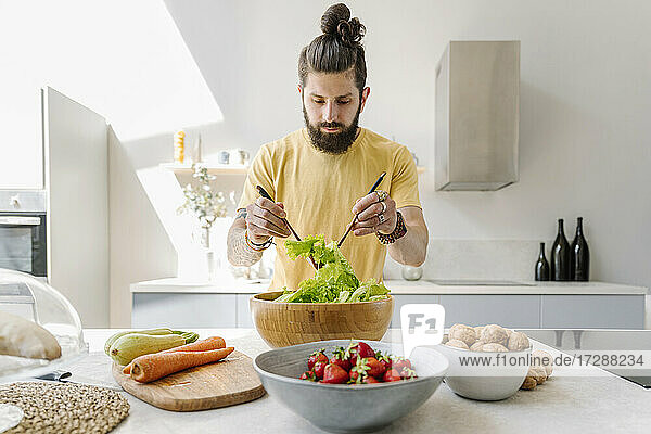 Mann mischt Gemüse bei der Zubereitung von Salat zu Hause