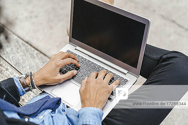 Businessman using laptop while sitting on bench