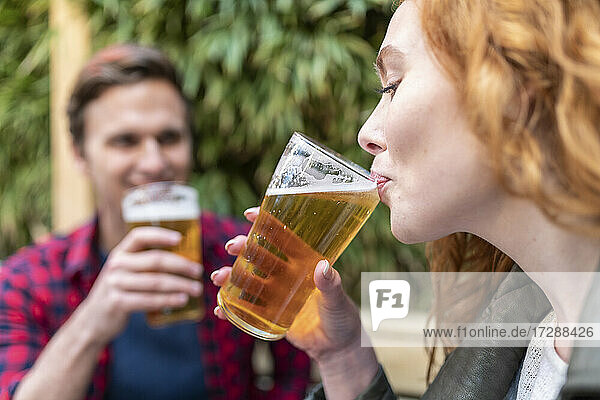 Frau trinkt Bier in einem Glas in einer Kneipe