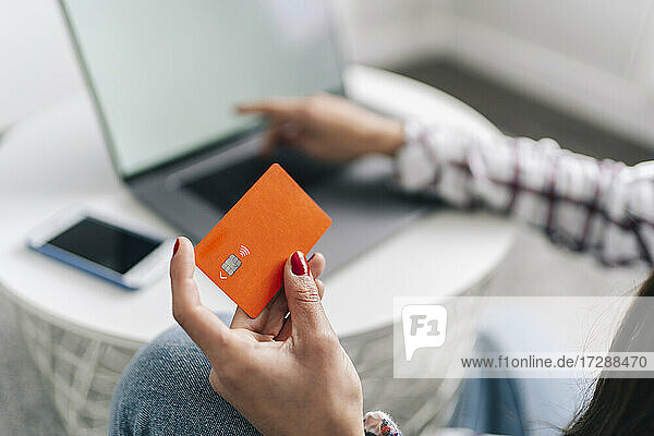 Frau mit Kreditkarte beim Online-Einkauf über Laptop zu Hause