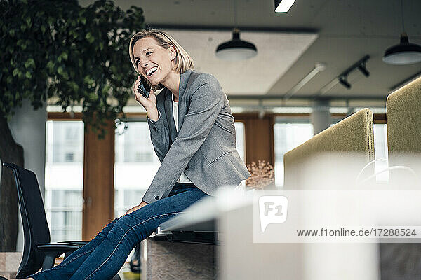 Lächelnde Geschäftsfrau  die im Büro mit einem Mobiltelefon spricht