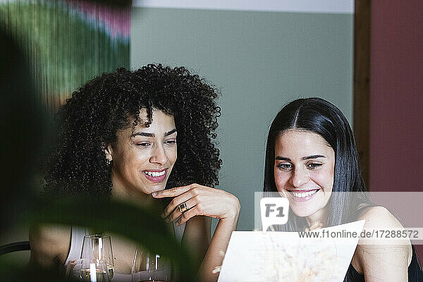 Lächelnde Freunde lesen Speisekarte im Restaurant