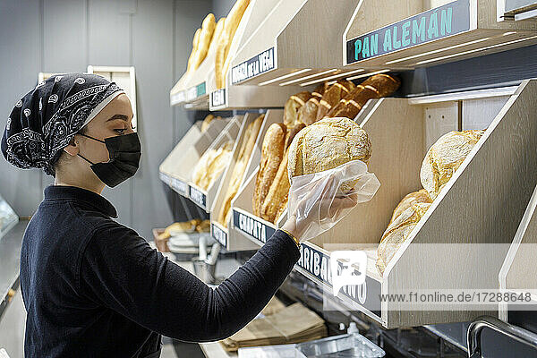 Female baker wearing mask working in bakery