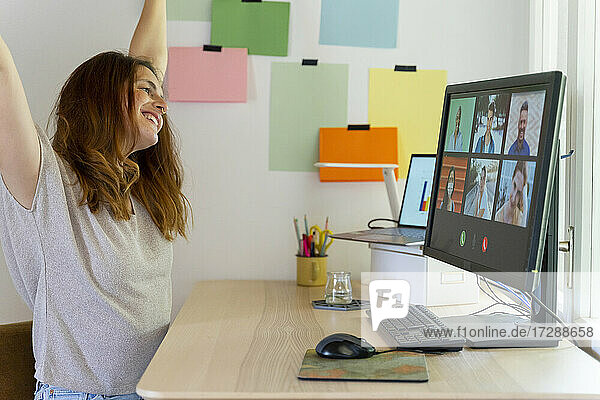 Fröhliche Geschäftsfrau bei einem Videogespräch am Computer am Schreibtisch im Heimbüro