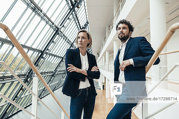 Männliche und weibliche Fachkräfte  die beim Stehen im Büro wegschauen