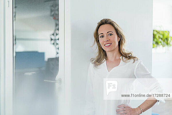 Geschäftsfrau mit Hand auf der Hüfte vor einer schalldichten Kabine im Büro stehend