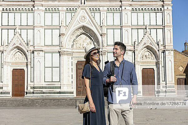 Smiling couple standing in front of Basilica Of Santa Croce on sunny day at Florence  Italy
