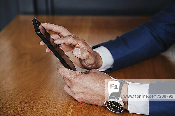 Businessman using smart phone on wooden table
