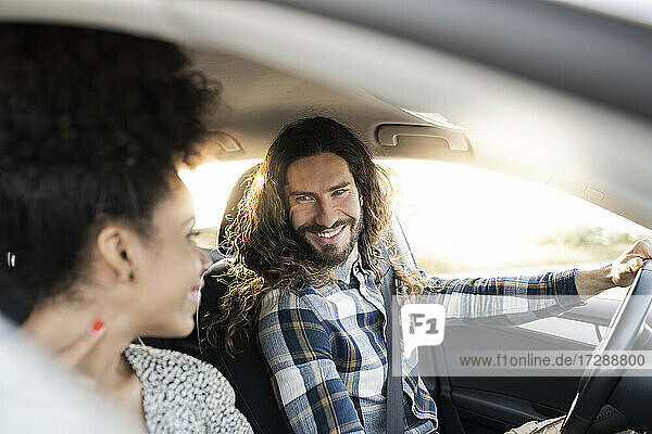 Lächelnder Freund schaut seine Freundin an  während er Auto fährt