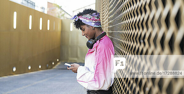 Junge Frau mit Kopftuch benutzt ihr Smartphone an der Wand