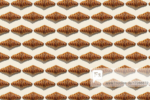 Butter croissants in a row on beige background