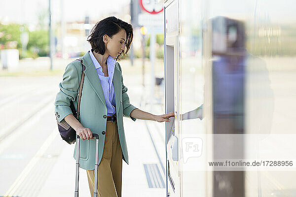 Geschäftsfrau kauft Zugfahrkarte am Bahnhof