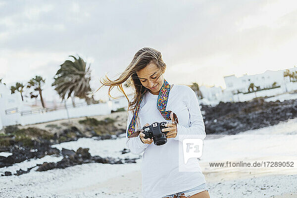 Junge Frau mit Kamera am Strand stehend