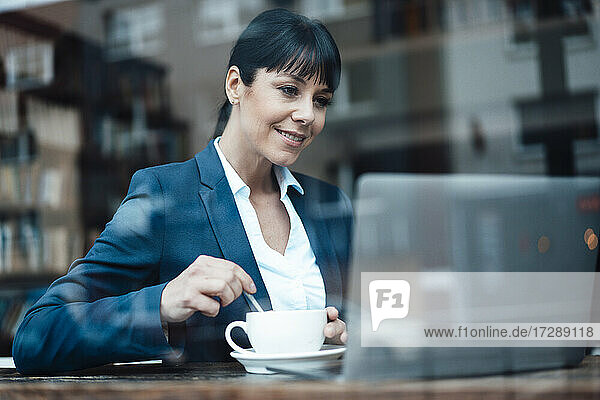 Lächelnde Unternehmerin mit Laptop in einem Cafe