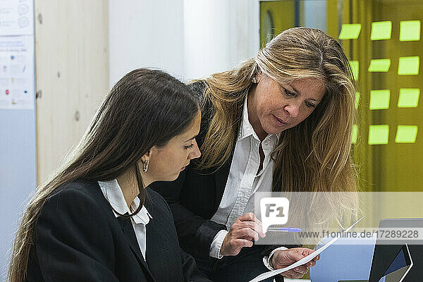 Businesswoman with blond hair explaining business plan to female coworker in office