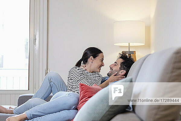 Happy girlfriend and boyfriend sitting on sofa in living room