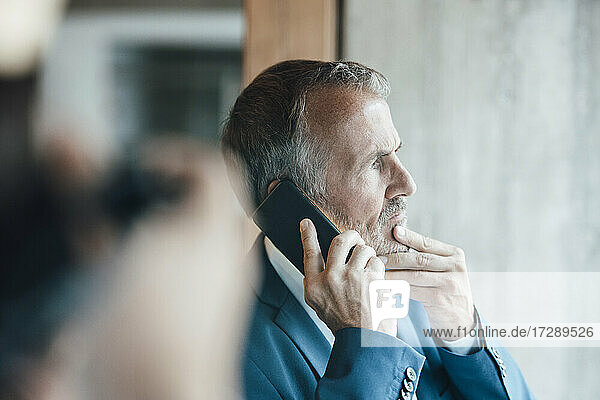 Senior businessman talking on mobile phone in office