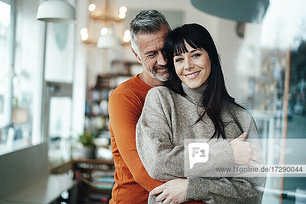 Smiling man embracing woman in cafe