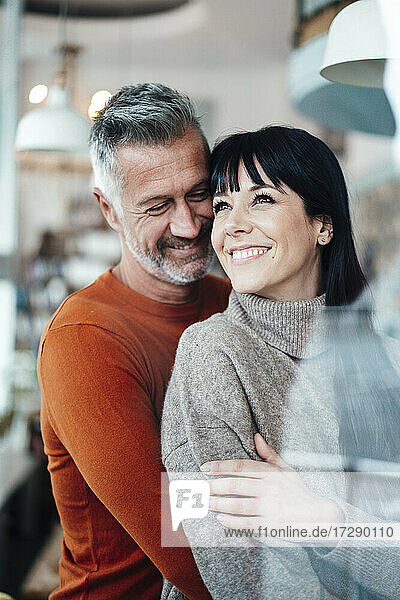 Lächelndes reifes Paar steht zusammen in einem Cafe
