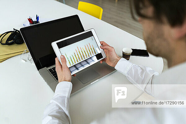 Male entrepreneur checking graph on digital tablet while working at office