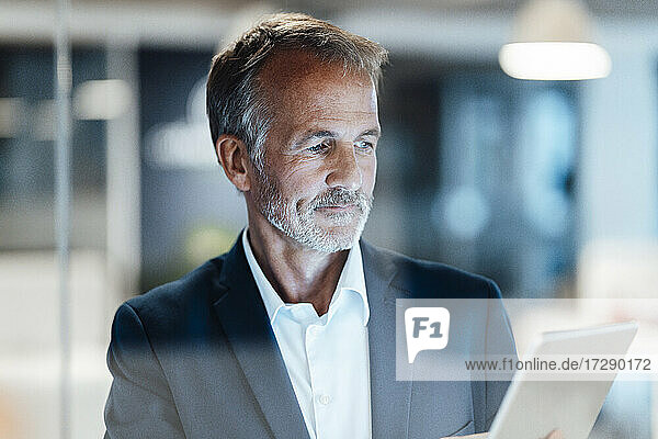 Ein älterer männlicher Unternehmer benutzt ein digitales Tablet im Büro