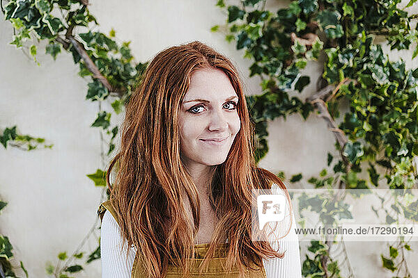 Beautiful redhead woman in front of vine plants