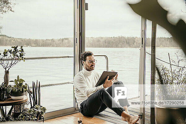 Männlicher Freiberufler mit digitalem Tablet auf einem Hausboot