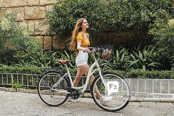 Junge Frau mit Fahrrad auf dem Fußweg
