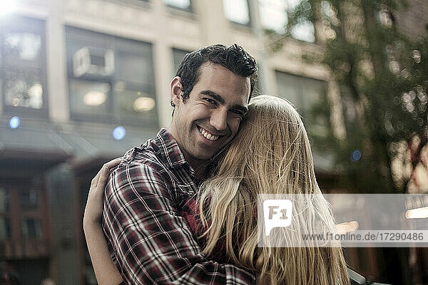 Smiling boyfriend embracing girlfriend in city
