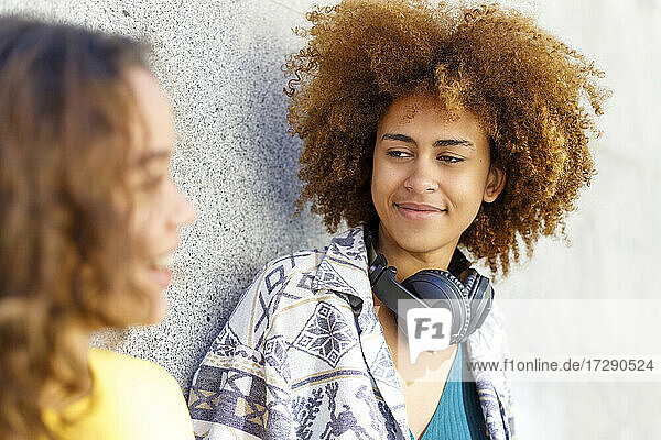 Afro young woman with female friend against wall