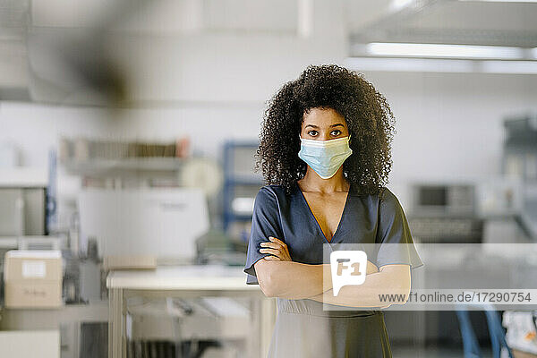 Mid adult businesswoman wearing protective face mask standing in industry during COVID-19