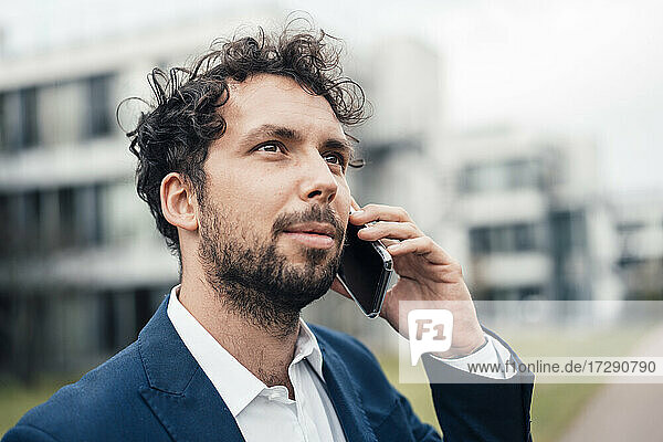 Geschäftsmann schaut weg  während er mit einem Mobiltelefon spricht