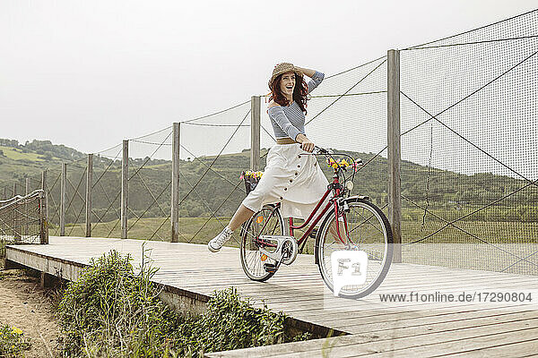 Unbekümmerte Frau fährt mit dem Fahrrad auf der Seebrücke
