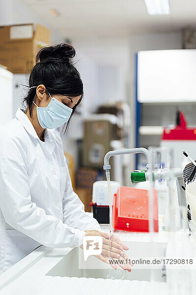 Ältere Forscherin mit Gesichtsschutzmaske beim Händewaschen im Labor
