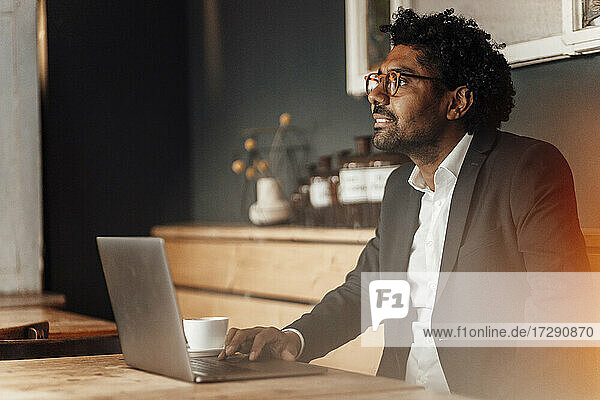 Männlicher Unternehmer mit Laptop am Tisch im Café sitzend