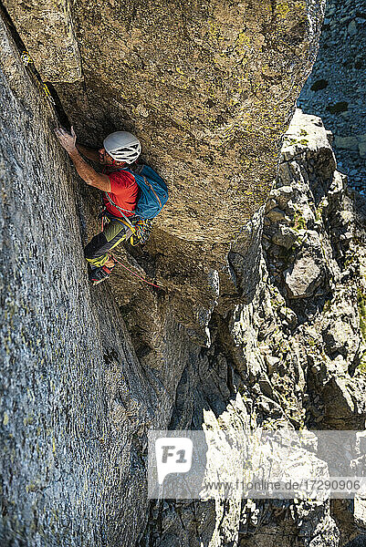 Mann klettert an einer Felswand  während er sich in den Bergen bewegt