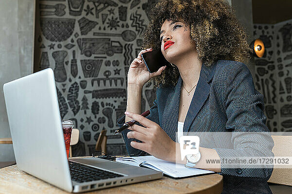Female freelance worker talking on mobile phone at coffee shop